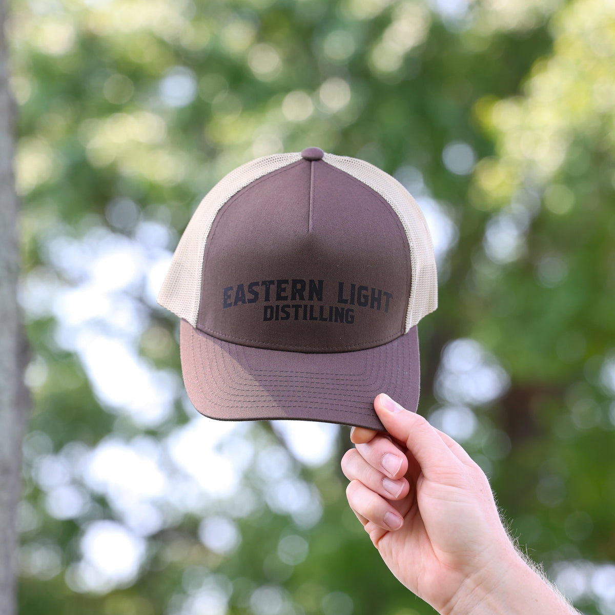 Eastern Light Distilling Brown Baseball Hat in Coyote and Beige with Outdoor Lifestyle background